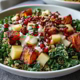 Vibrant vegetarian grain bowl featuring massaged kale, fluffy quinoa, and colorful roasted vegetables, finished with a zesty apple cider vinaigrette.  