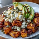 Golden roasted sweet potato cubes paired with sliced avocado, cottage cheese, and a drizzle of hot honey for a vibrant vegetarian meal.  
