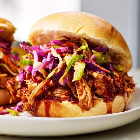 Savory pulled chicken sandwich piled high with tangy slaw on a buttery toasted bun.