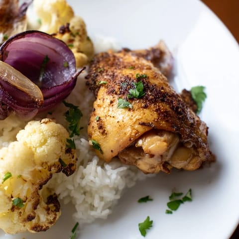 Tender chicken and caramelized cauliflower florets roasted with red onion on a single sheet pan, garnished with cilantro and served over basmati rice.