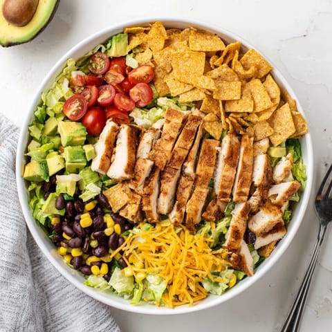 Vibrant Tex-Mex Crunchy Taco Chicken Salad in a white bowl, featuring juicy taco chicken, cherry tomatoes, green onions, and golden crushed shells for a satisfying crunch.