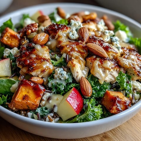 Harvest bowl with roasted chicken, sweet potatoes, kale, apples, almonds, and goat cheese in balsamic dressing.