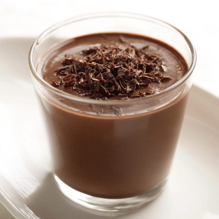 A close-up of decadent, rich chocolate pudding in a clear glass, perfect for sharing.