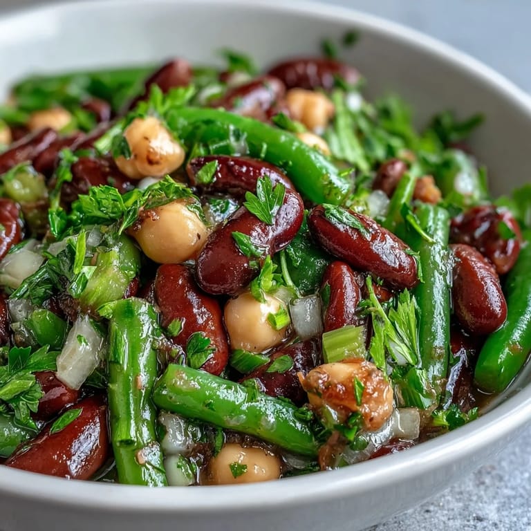Chilled Three-Bean Salad in a white bowl, featuring a colorful medley of beans and crisp celery slices, perfect for a refreshing side dish at a picnic.