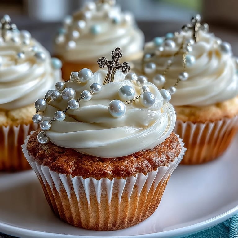 Delicate buttercream-frosted mini cupcakes adorned with handcrafted fondant rosary toppers, perfect for First Communion gatherings.