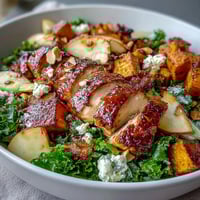 A hearty fall harvest bowl with roasted sweet potato, tender chicken, crisp apple, and creamy goat cheese, drizzled with tangy balsamic vinaigrette.