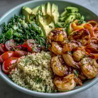 Vibrant rainbow vegetable detox bowl with quinoa, shrimp, and avocado, dressed in tangy balsamic vinegar for a nourishing meal.